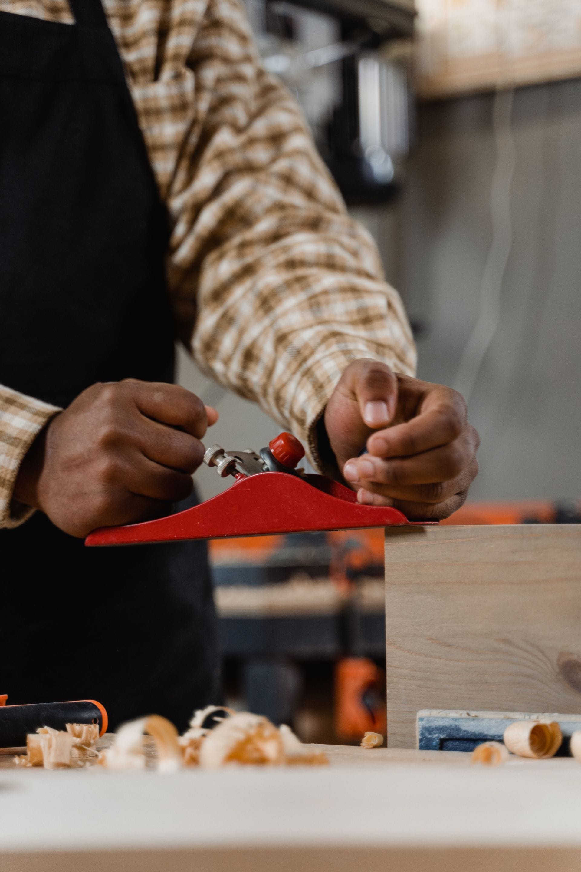 Carpenter planing an oak board at a workbench in a joinery workshop